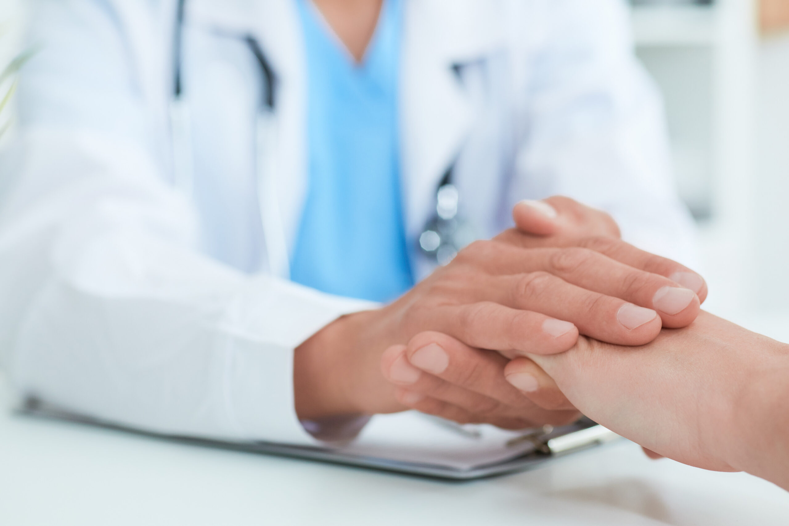 Hand of doctor reassuring her female patient. Medical ethics and trust concept